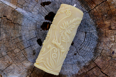 Cream beeswax pillar candle featuring intricate botanical relief carvings