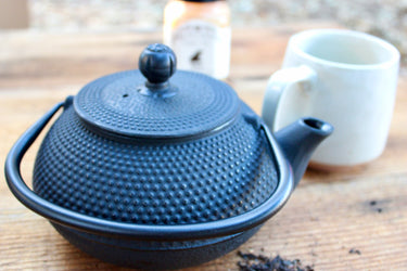Close-up of hobnail textured black cast iron teapot lid knob and spout detail