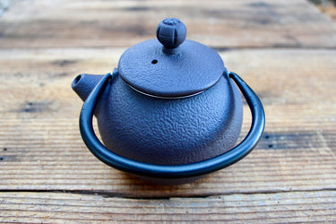 Brown cast iron tea pot with textured finish and arched handle