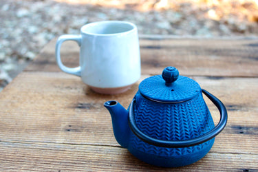 Rustic peacock blue enameled cast iron teapot on wooden table