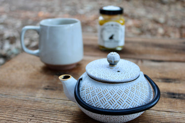 White cast iron tea pot with diamond texture and black handle