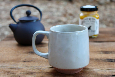 Close-up of speckled oatmeal glaze and unglazed terracotta base on tea cup