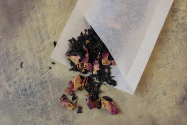 Close-up of natural unbleached single use tea filter showing ribbed texture and floral contents