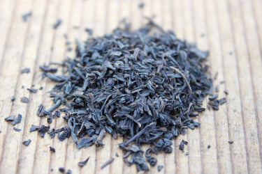 Organic Earl Grey loose-leaf black tea with dark twisted leaves on wood