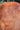 Extreme close-up of smooth polished Madrone wood texture with concentric rosy gold swirls