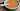 Orange-brown bone broth with herbs in ceramic bowl