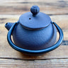 Brown cast iron tea pot with textured finish and arched handle