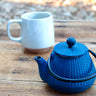 Rustic peacock blue enameled cast iron teapot on wooden table