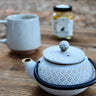 White cast iron tea pot with diamond texture and black handle