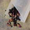 Close-up of natural unbleached single use tea filter showing ribbed texture and floral contents